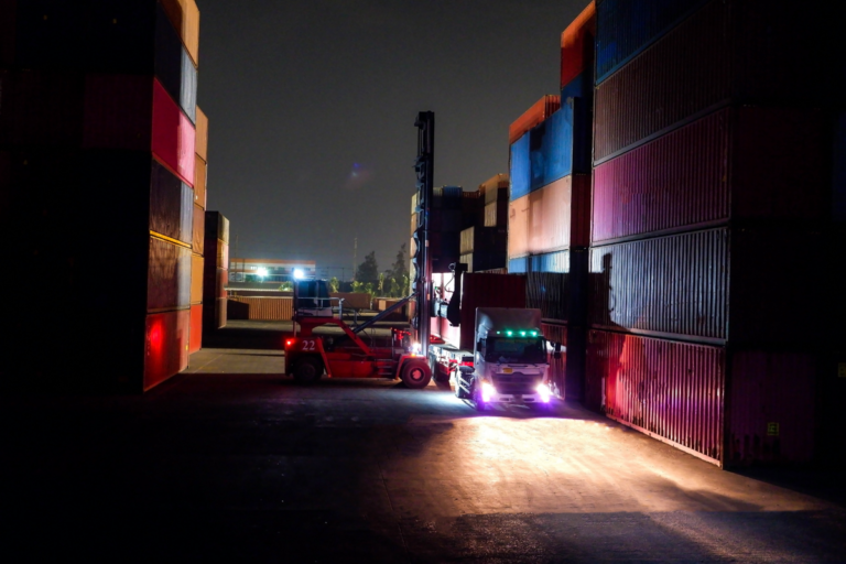 Headlights cut across an empty container lane after dark, the hours when holiday cargo theft happens